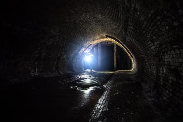 Old vaulted sewer tunnel with dirty sewage water. Underground river Neglinnaya flowing under Moscow