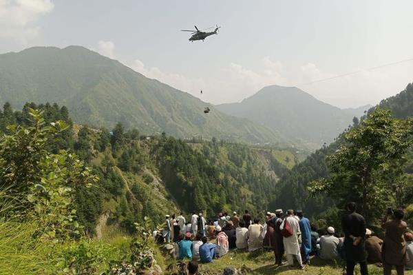 People watch as an army soldier slings down from a helicopter during a rescue mission Tuesday.