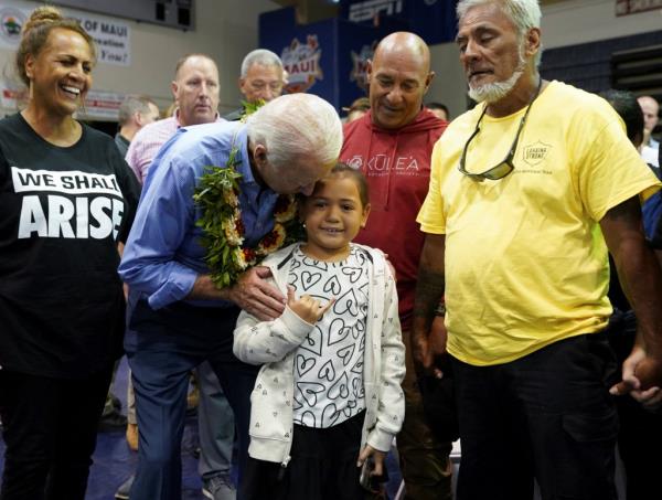 A young girl gives a shaka sign as U.S. President Joe Biden speaks to her during a community event at the Lahaina Civic Center.