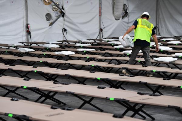 A worker laying out pillows for the cots in the migrant "Tent City" on Randall's Island before it opened.