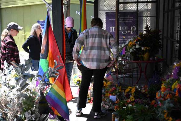 People gather at makeshift memorial with flowers outside Mag.Pi store. 