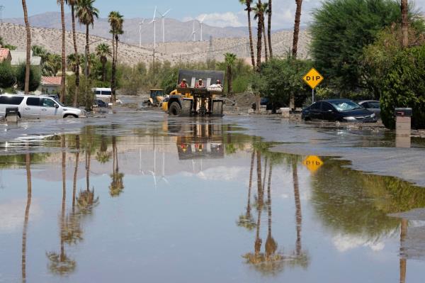 Firefighters use a skip loader to rescue a person from an assisted living center after the street was flooded with mud on Aug. 21, 2023, in Cathedral City, Calif. 