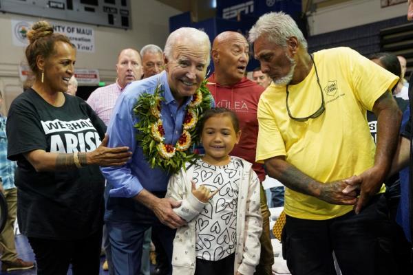 A young girl gives a shaka sign as she poses with U.S. President Joe Biden